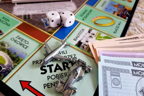 Plansza Monopoly z pionkami (samolot, bolid), kostkami i banknotami.
