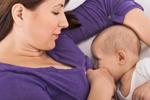 En mamma ammar sitt barn i en liggande position, en av många olika amningspositioner.