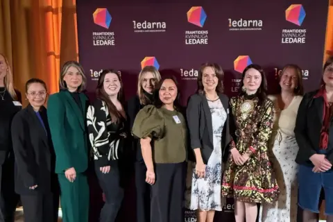 Gruppbild på tio kvinnor framför en bakgrund med texten "Framtidens kvinnliga ledare". De ser ut att vara deltagare i ett ledarskapsprogram.