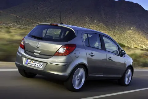 Szary Opel Corsa D 1.2 benzyna w ruchu, z widokiem na tył, na tle górskiego krajobrazu.