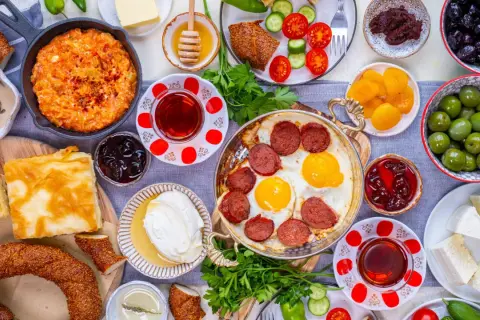 Reichhaltiges türkisches Frühstück: Eier mit Sucuk, Käse, Oliven, Honig und Gebäck. Welches Lebensmittel hat die meisten Kalorien? Wahrscheinlich das Gebäck oder die Wurst.