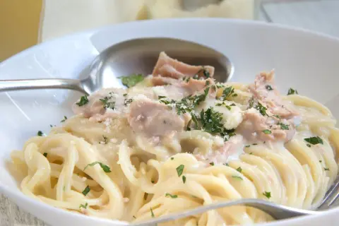 Cremige Nudeln mit Thunfisch, garniert mit Petersilie und Parmesan. Ein köstliches Gericht, das Lust auf mehr macht.