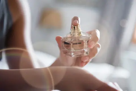 Dłoń trzyma flakonik perfum, a subtelny zapach unosi się w powietrzu. Envy me, Gucci.
