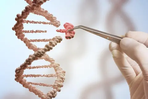Ręka w rękawiczce trzyma pęsetą fragment DNA, jakby tworząc jego klon.