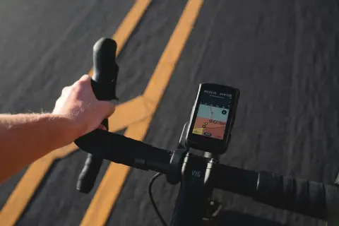 Dłoń na kierownicy roweru, nawigacja pokazuje mapę tras rowerowych w Krakowie.