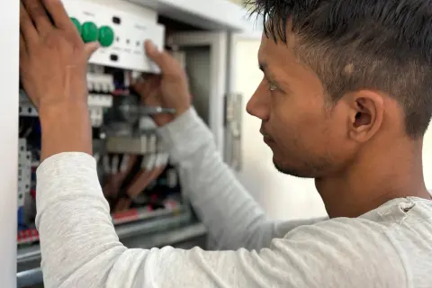 Elektryk montuje panel sterowania w skrzynce elektrycznej.