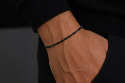 Pulsera barbada oro con diamantes negros en muñeca masculina. Elegancia y estilo en cada detalle.