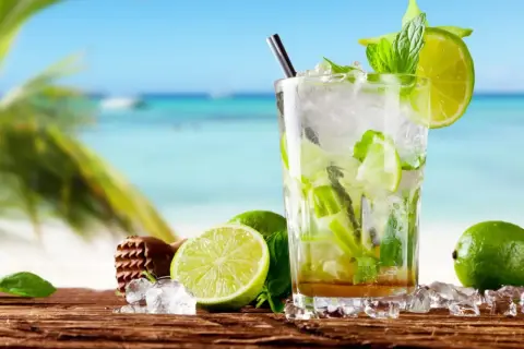 Orzeźwiający mohito alkohol z limonką i miętą na tle plaży. Idealny na wakacje!