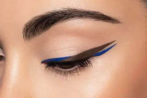 Occhio con eyeliner grafico marrone e blu elettrico, un audace cat crease che cattura lo sguardo.