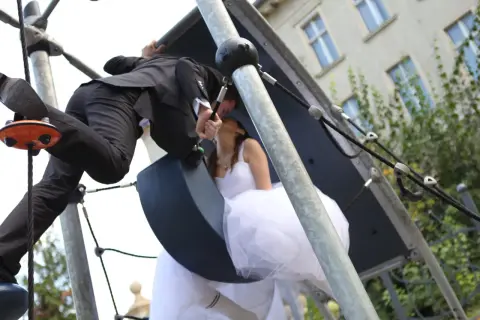 Młoda para w ślubnych strojach całuje się na placu zabaw. Czy lakarnum ma narzeczoną? Tak, i to piękną!