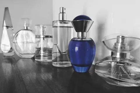 Rząd flakonów perfum, w tym Chanel i niebieski flakon, budzi pytanie: czy perfumy są szkodliwe?