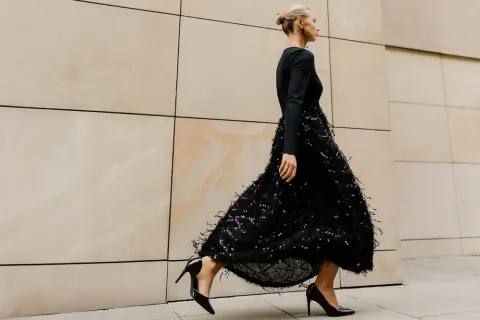 Elegancka kobieta w czarnej sukience z cekinami i piórkami, czarne szpilki. Idealne dodatki do czarnej cekinowej sukienki.