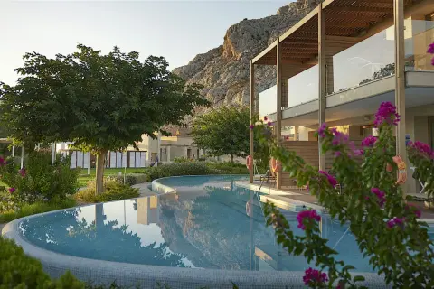 En vacker pool reflekterar bergen vid aegean park rhodos. Blommor och grönska omger hotellet.