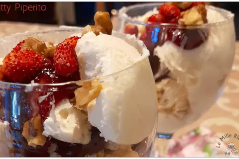 Coppa con gelato allo yogurt greco, fragole fresche, salsa rossa e noci croccanti. Un dessert fresco e goloso.