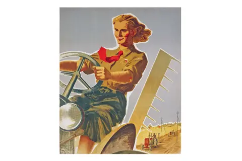 Kobieta za kierownicą traktora, symbol emancypacji kobiet i ich roli w rolnictwie. W tle inne traktory pracujące na polu.