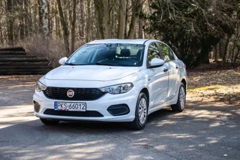 Biały Fiat Tipo sedan zaparkowany na leśnej drodze.