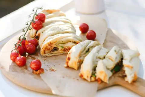 Ein köstlicher Stromboli, gefüllt mit Tomaten, Oliven und Käse, wird mit frischen Kirschtomaten garniert. Perfekt zum Stromboli essen!
