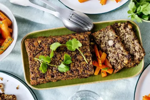 Herzhaftes Linsen-Nuss-Brot mit glasierten Karotten – ein köstliches vegetarisches Weihnachtsessen, garniert mit frischer Petersilie.