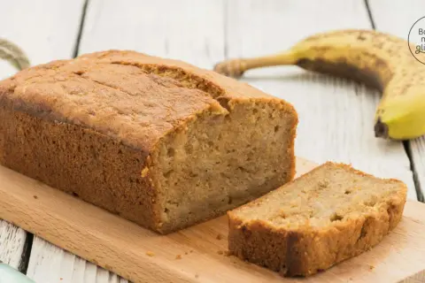Saftiges Bananenbrot mit Dinkelmehl, frisch gebacken und auf einem Holzbrett angerichtet. Eine Scheibe ist bereits abgeschnitten.