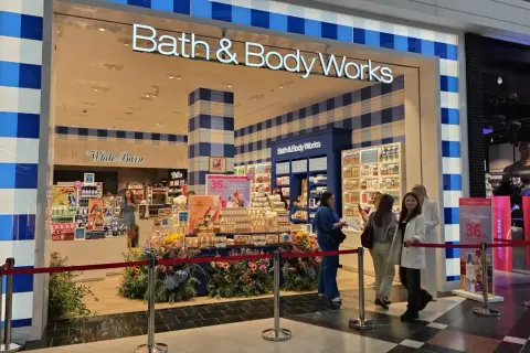 Sklep Bath & Body Works z promocjami, wystawą kwiatów i klientami.