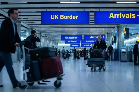Na lotnisku w UK, podróżni z bagażami kierują się do odprawy. Zastanawiasz się, ile alkoholu do UK możesz przywieźć?