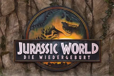 Das Logo von Jurassic World: Die Wiedergeburt, mit einem T-Rex-Kopf, bereit für den Jurassic World Stream.