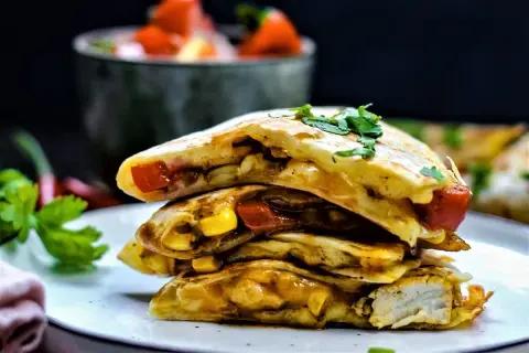 Gestapelte Quesadillas mit Hähnchen, Mais und Tomaten, garniert mit Koriander. So sieht eine leckere Quesadilla aus!