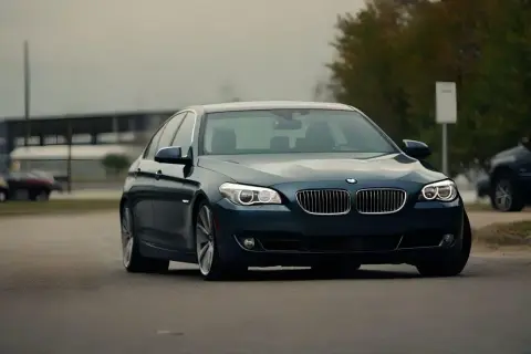 Ciemnoniebieskie BMW na drodze, może symbolizować odstąpienie od umowy kupna samochodu.