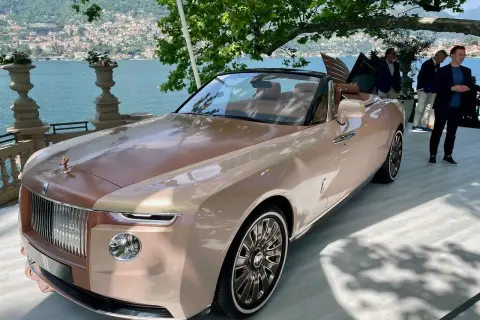 Elegancki Rolls-Royce Boat Tail w kolorze szampańskim, prezentowany nad jeziorem Como, przyciąga wzrok swoim unikalnym designem.