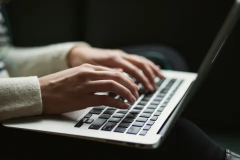 Dłonie piszą na laptopie, być może pracując nad zadaniem dla **windows modules installer worker**.