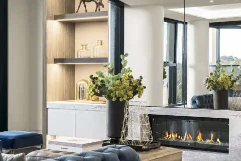 Un elegante camino bioetanolo come funziona: fiamme vive su un letto di sassi bianchi, con decorazioni moderne e arredi di lusso.