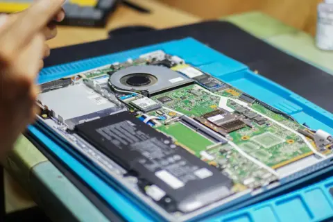 Naprawa laptopa. Widać płytę główną z baterią, wentylatorem i modułami, być może porównanie NGFF vs NVMe.