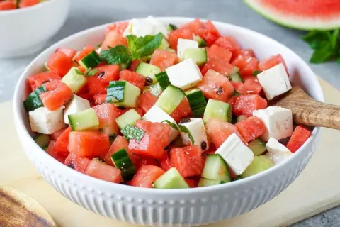 Erfrischender Melonensalat mit Mozzarella, Gurken und Minze in einer weißen Schüssel. Perfekt für heiße Tage!