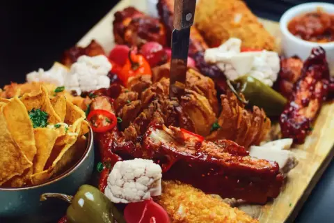 Talerz pełen pyszności: żeberka, skrzydełka, nachos i chrupiąca cebula. Idealna uczta, którą znajdziesz w najlepszych restauracjach w Sopocie.