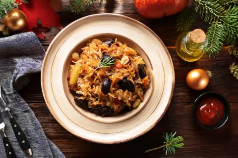 Pyszny bigos z kiszonej kapusty, podany na talerzu, z dodatkami i świątecznymi ozdobami.