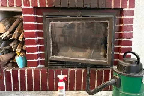 Preparativos para como deshollinar una chimenea: leña, aspiradora y spray limpiador.