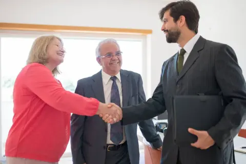 Coppia anziana stringe la mano a un consulente finanziario, discutendo del mutuo fino a che età.