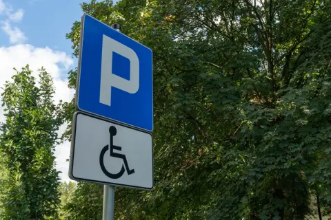 Znak parkingowy z symbolem osoby na wózku inwalidzkim, wskazujący miejsca dla osób z różnymi stopniami niepełnosprawności.