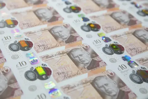 Nowe funty brytyjskie banknoty z wizerunkiem króla Karola III, w tle widać poprzednie banknoty z królową Elżbietą II.