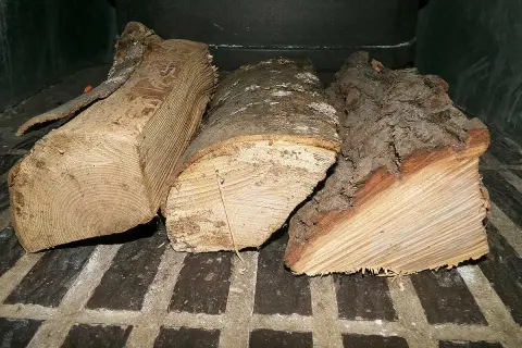Trois bûches de bois de chauffage, prêtes à être consumées, dégagent l'essence de bois de chauffage.