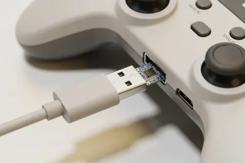 Szary kontroler z podłączonym kablem USB. Dowiedz się, jak podłączyć pada od PS4 do Xbox One, używając tego adaptera.
