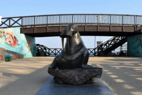 Mielno pomnik morsa przy malowniczej kładce z muralami.