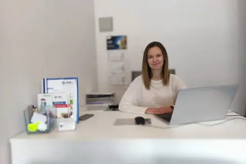 Kobieta przy biurku z laptopem i dokumentami.
