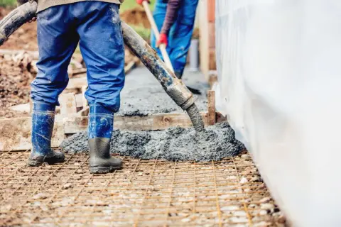 Pracownicy wylewają beton na zbrojenie. Wiedząc, ile waży kubik betonu, można oszacować ciężar tej budowy.