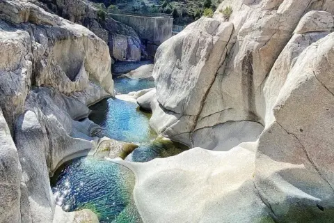 Pozzo di roccia con acqua cristallina, un luogo ideale per rinfrescarsi tra le cascate in Sardegna dove fare il bagno.