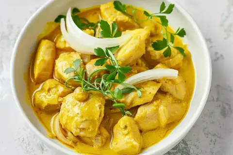 Kyckling i krämig currysås, perfekt för ett snabbt currysås recept. Garnerad med lök och persilja.