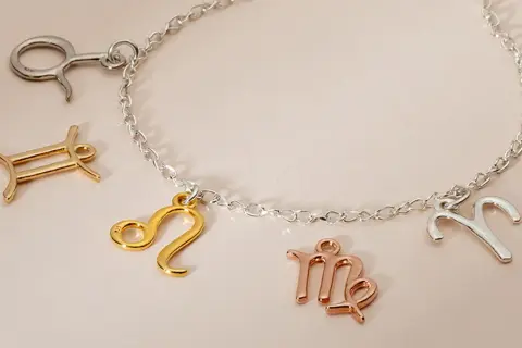 Bransoletka z zawieszkami w kształcie znaków zodiaku. Niektóre zawieszki mają piękne kolory złota, inne są srebrne lub w odcieniu różowego złota.