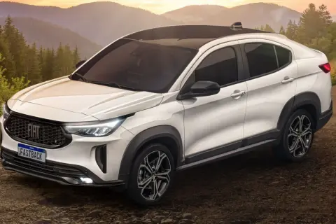 Bianca Fiat Fastback 2026 con tetto nero, su strada sterrata tra alberi e montagne al tramonto.