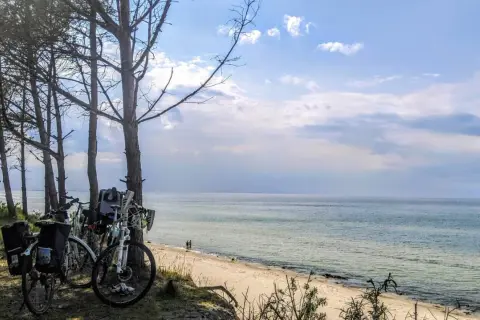 Rowerowe wycieczki to jedne z najlepszych mrzeżyno atrakcje. Rowery zaparkowane przy plaży, morze i niebo.