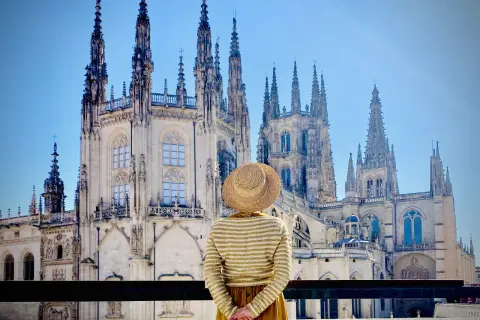 Una persona con sombrero admira la majestuosa Catedral de Burgos, considerada por muchos la mejor catedral de España, con sus imponentes agujas y detalles góticos.
